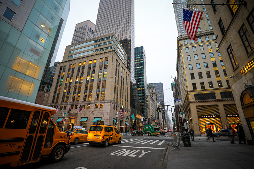 New York, USA - 03 29 2018: Fifth Avenue in Manhattan early morning traffic with yellow taxi cabs and cars. Fifth Avenue in New York City known for its luxury retail shops.