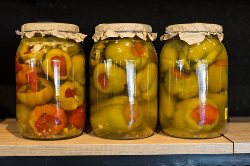 Three jars of fermented stuffed green bell peppers on a shelf