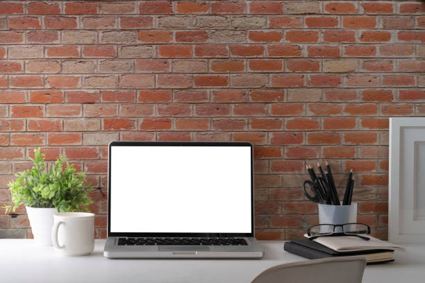 istock Laptop computer, coffee cup, picture frame and potted plant on white table. Blank screen for your advertise text. 1423328921