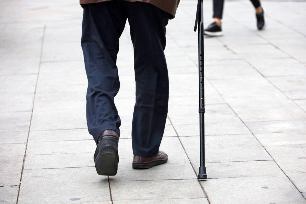 istock Old man walking with a cane down the city street 1423329192
