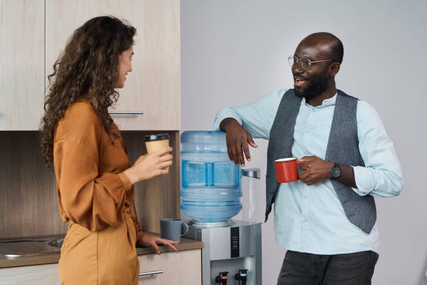 giovani impiegati interculturali felici che bevono tè e caffè durante la pausa - cooler foto e immagini stock