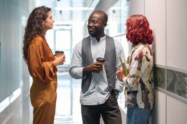istock Three young successful office managers in casualwear having chat in corridor 1423335051