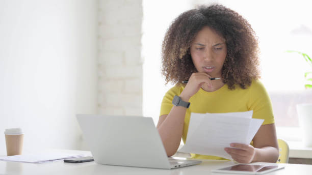 istock African Woman with Laptop Having Loss while Reading Documents 1423335508