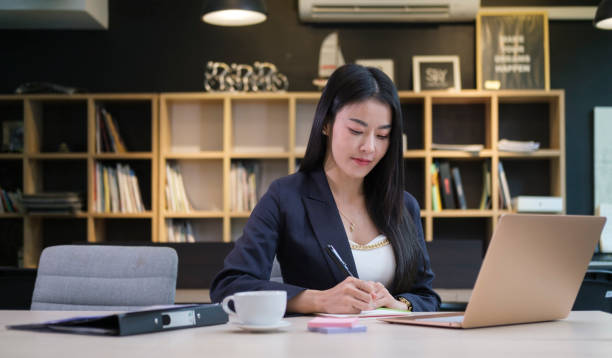 istock Professional businesswoman working with laptop computer and writing business plan on notepad. 1423336301
