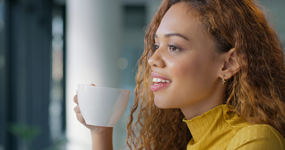 Coffee break, relax and thinking woman drinking espresso or tea in the morning with a vision, inspiration goal or mindset.  Happy young black woman with cup enjoying fresh warm beverage indoors