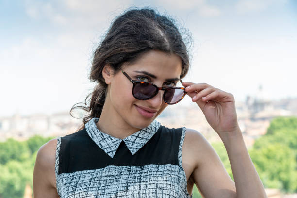 Woman looking at Rome as seen from Monumento a Garibaldi, with sunglassesRight hand leaning on wall, looking at camera