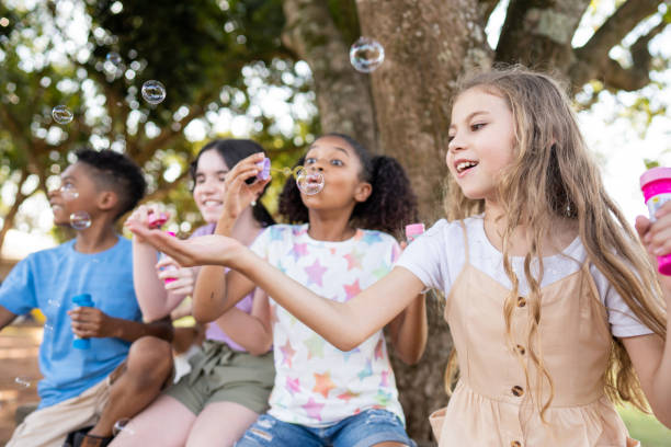grupo de niños jugando con pompa de jabón - bubble wand bubble child playful fotografías e imágenes de stock