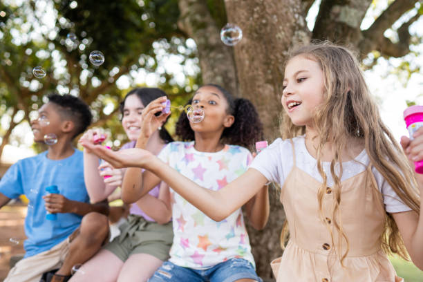 groupe d’enfants jouant avec des bulles de savon - bubble wand child outdoors bubble photos et images de collection