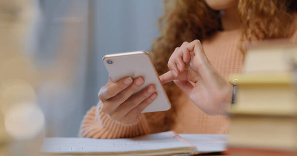Phone, internet and social media app scroll of a student taking a break for studying books. Mobile technology of a woman online with a notebook and library book looking at digital web content