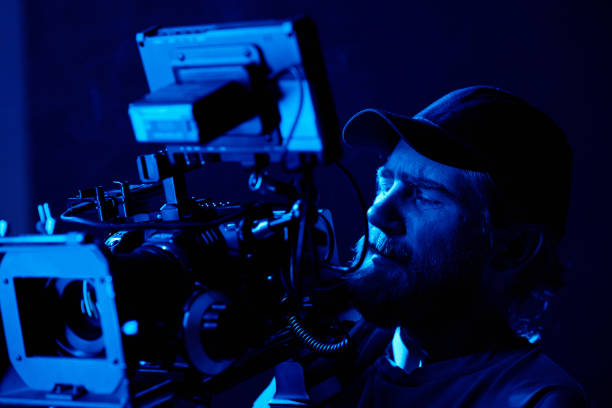 istock Bearded man in baseball cap looking on small screen on video camera 1423343382