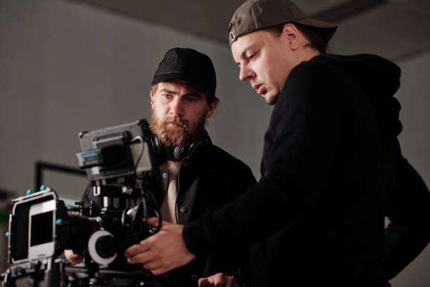 istock Two serious men in black sweatshirta discussing settings of steadicam 1423343438