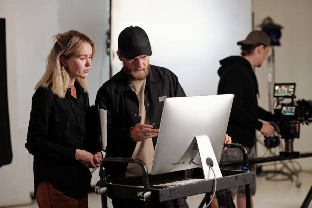 istock Young videographer and his assistant having discussion in front of computer 1423343449