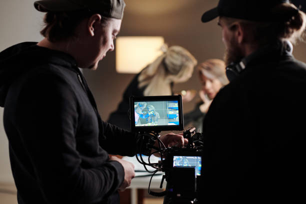 istock Two young men in black shirts adjusting focus of camera during shooting 1423343467