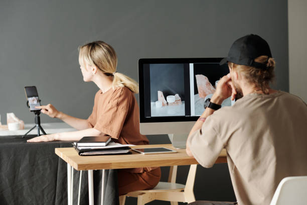 istock Young photographer sitting in front of computer and female assistant 1423343512