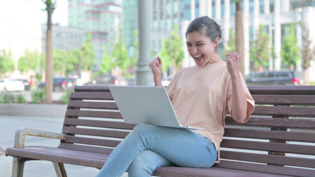 istock Indian Woman Celebrating Success while using Laptop Outdoor 1423345783