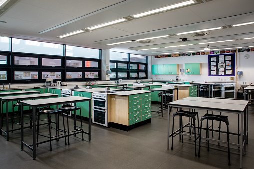 A home economics classroom filled with desks, chairs, workbenches and cooking equipment in a secondary school in the North East of England.