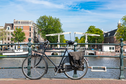 Amsterdam bicycle on a bridge with the river Amstel in the background and a blue sky in the background.