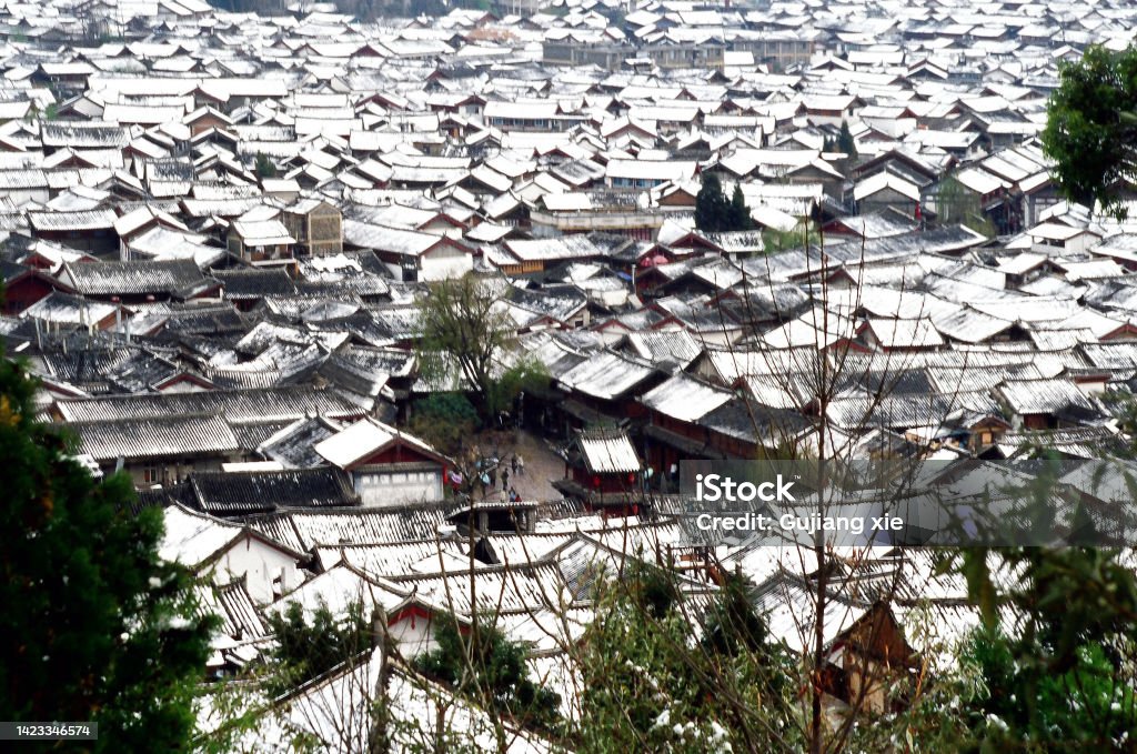 The old town of Lijiang  and Square Market after snow Although located at the foot of the Jade Dragon Snow Mountain, the old town of Lijiang is warm in winter and rarely snows. In some winters the snow falls, and then it melts completely within an hour or two. Therefore, the snow scenery of the Old Town is rare. Photographic slide photo in  Feb 2005, Lijiang 2000-2009 Stock Photo