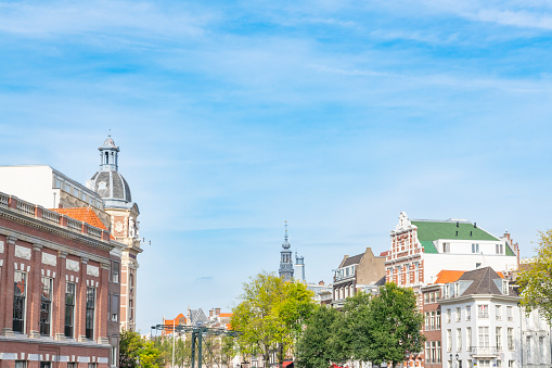 Amsterdam canal house facades with a blue sky in the background during summer.