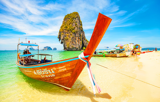 Krabi, Thailand - 12 March, 2022: Sunny tropical beach Phra Nang near Ao Nang town, traditional longtail boat on a foreground