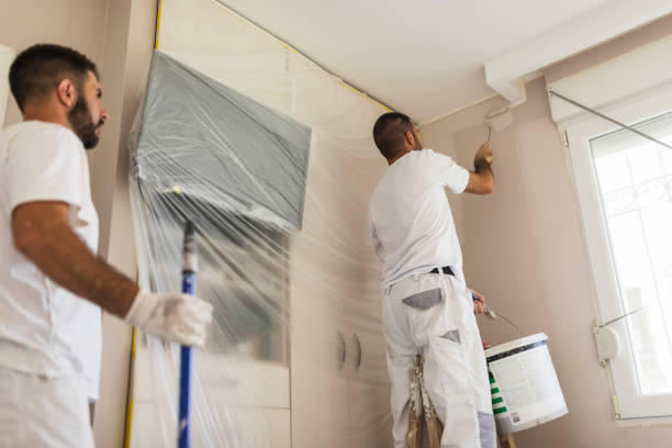 Two men redecorating the room together, painting the ceiling stock photo