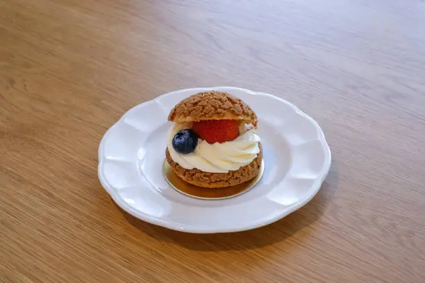 Photo of Homemade choux cream or cream puffs with custard cream and strawberry. Homemade bakery concept.