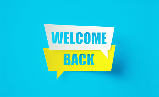 Welcome back written cut out yellow and white speech bubbles sitting on blue background. Horizontal composition with copy space.