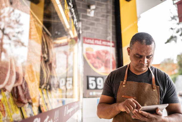 geschäftsinhaber mit digitalem tablet inventur in einer metzgerei - supermarket meat store manager stock-fotos und bilder
