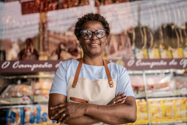 portrait of a female butcher's shop owner - supermarket meat store manager imagens e fotografias de stock