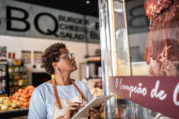 empresário com tablet digital fazendo inventário em um açougue - supermarket meat store manager - fotografias e filmes do acervo