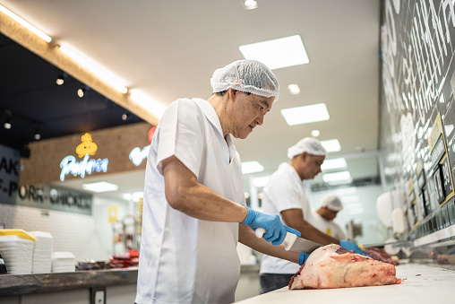 Butchers slicing meat in a butcher's shop