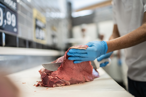 Male hands cutting meat in a butcher's shop