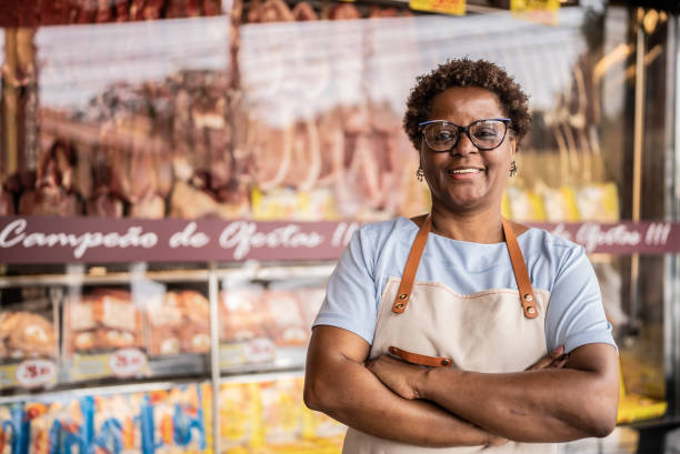 portrait of a female butcher's shop owner - supermarket meat store manager imagens e fotografias de stock