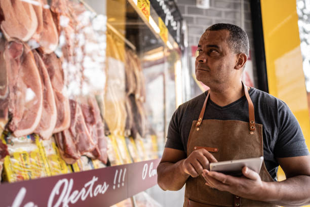 business owner with digital tablet taking inventory in a butcher's shop - supermarket meat store manager imagens e fotografias de stock