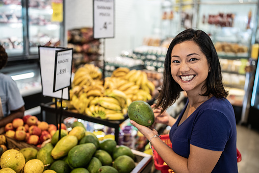 Portrait of a mid adult woman choosing papaya in a supermarket
