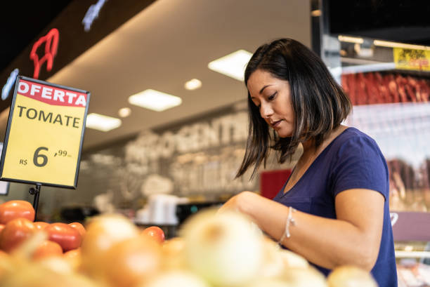 スーパーマーケットでトマトを選ぶ中年の女性 - convenience store merchandise consumerism customer ストックフォトと画像