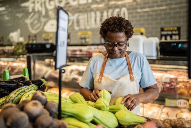 istock Employee arranging vegetables in a market 1423350767