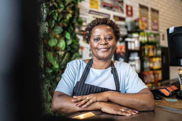 Portrait of a senior woman cashier working in a market Portrait of a senior woman cashier working in a market market vendor stock pictures, royalty-free photos & images