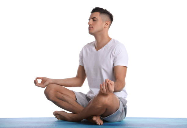 istock Handsome man meditating on yoga mat against white background 1423354235