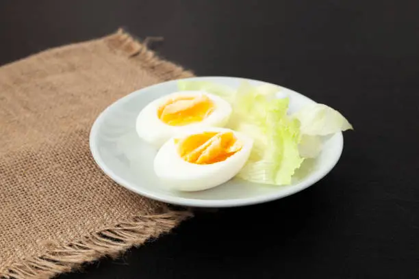 Hard boiled eggs on a plate with salad greens - side view