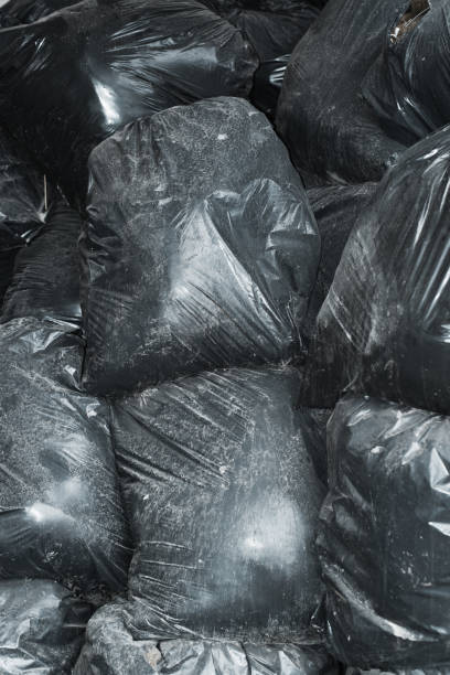 Background pile of dusty dirty black plastic bags with garbage stock photo