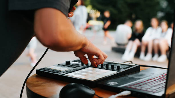 primo piano di un musicista beatmaker irriconoscibile che suona musica hip hop su un controller midi di batteria in un festival all'aperto e tiene in mano un microfono. messa a fuoco selettiva - instrumental hip hop immagine foto e immagini stock