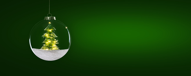 shiny hanging christmas tree ball on green background, beautiful xmas decoration isolated with bright lights, greeting card for happy new year and merry christmas with copy space