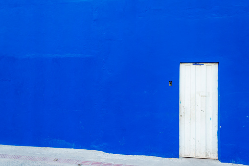 White metal door on a huge blue wall. Space for advertising.