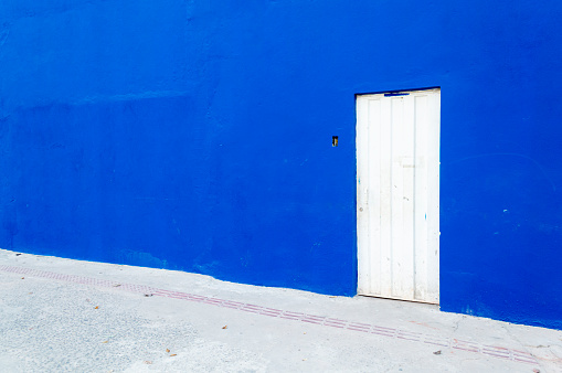 White metal door on a huge blue wall. Space for advertising.