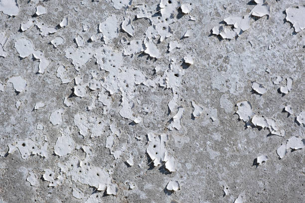 istock Old white concrete wall with cracks and peeling paint, close up 1423364090