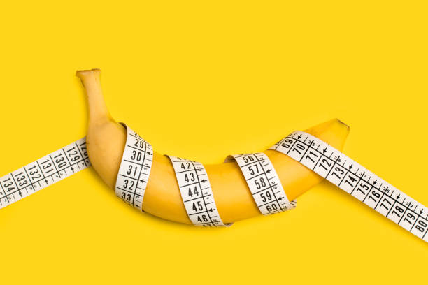 istock A banana with a measuring tape on a yellow background 1423365824