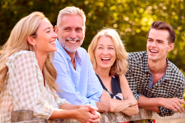 Multi-Generation Family With Adult Offspring Leaning On Fence Walking In Countryside stock photo