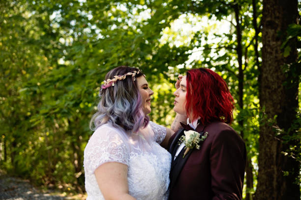 Portrait of newlywed brides tender moment outdoors in summer. Portrait of newlywed brides tender moment outdoors in summer. This is part of a series about a lesbian couple getting married. Horizontal outdoors waist up shot with copy space. gay wedding kiss stock pictures, royalty-free photos & images