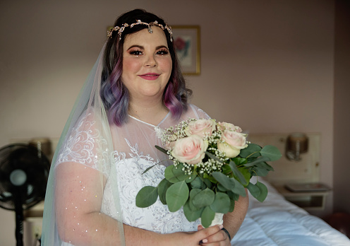 Portrait of beautiful body positive future bride ready for LGBTQ+ wedding. This is part of a series about a lesbian couple getting married. Horizontal indoors close-up shot with copy space.